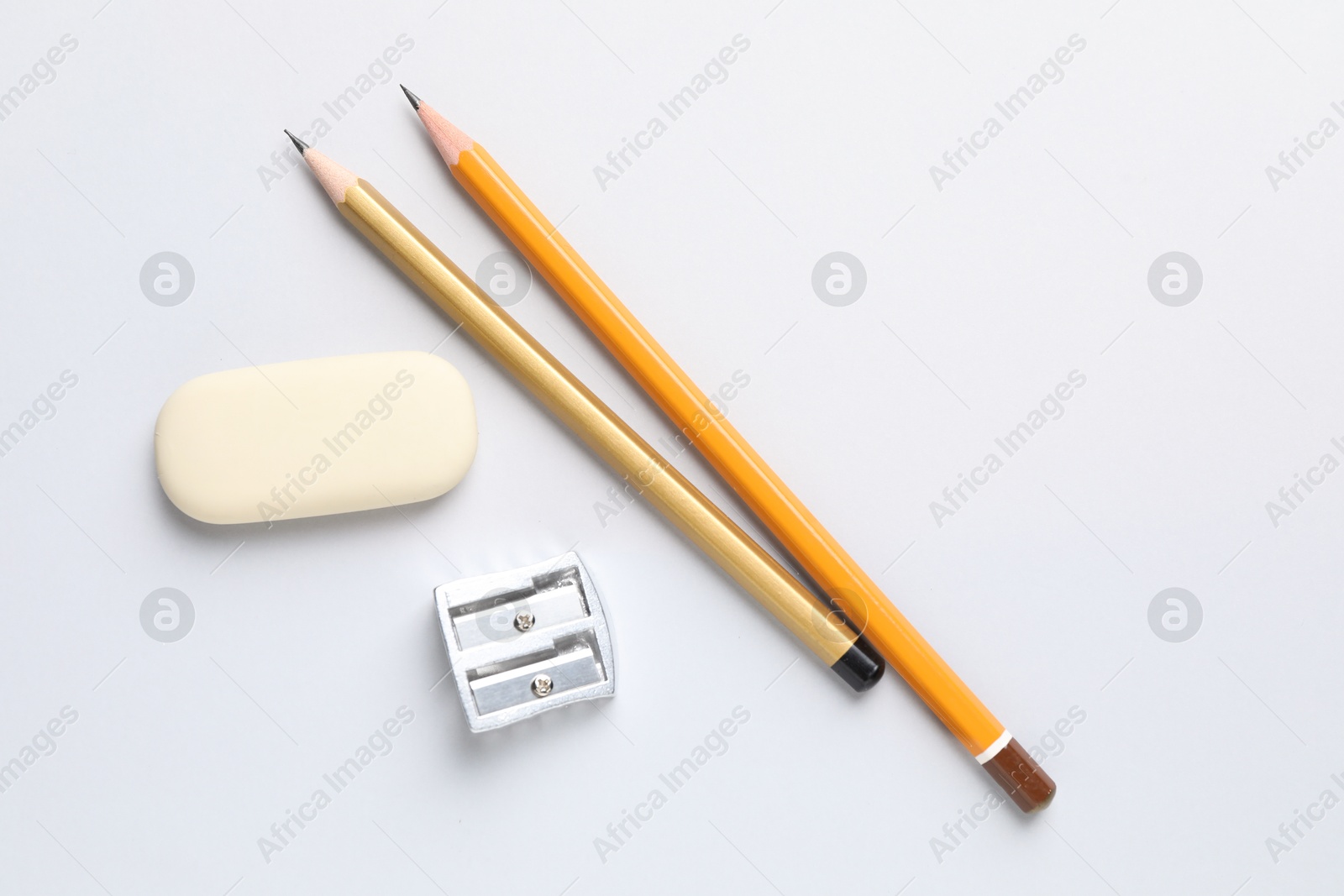 Photo of Eraser, pencils and sharpener on light background, top view