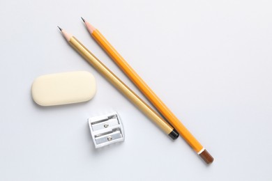 Photo of Eraser, pencils and sharpener on light background, top view