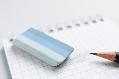 Photo of Eraser, pencil and notepad on light background, closeup