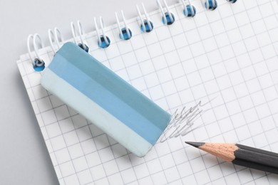 Photo of Eraser, pencil and notepad on light background, closeup