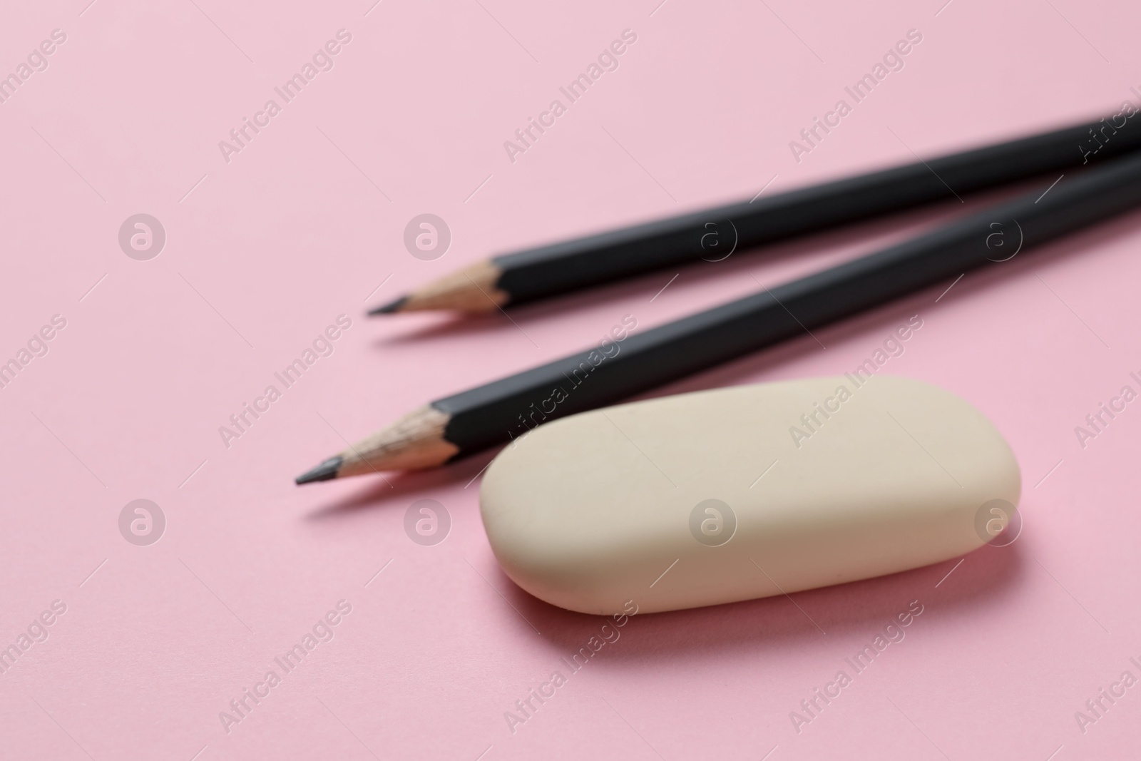 Photo of Eraser and pencils on pink background, closeup