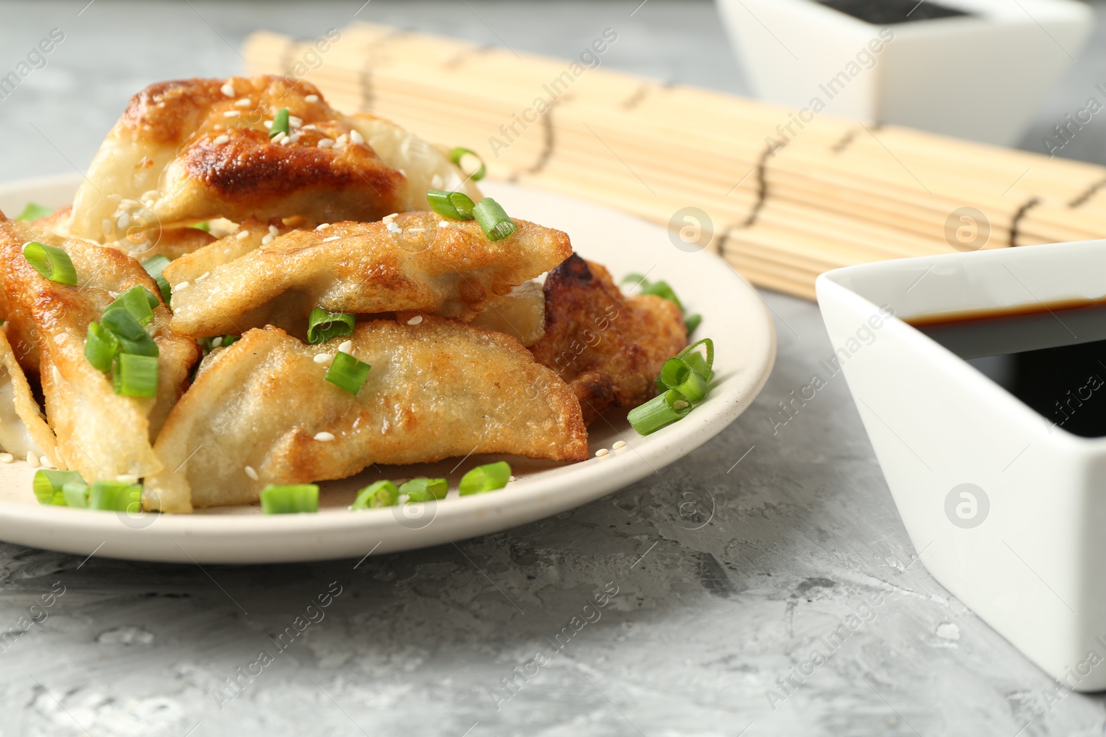 Photo of Tasty fried gyoza (dumplings) and soy sauce on light grey table, closeup