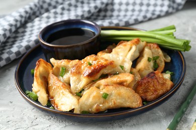 Photo of Tasty fried gyoza (dumplings) and soy sauce on light grey table, closeup