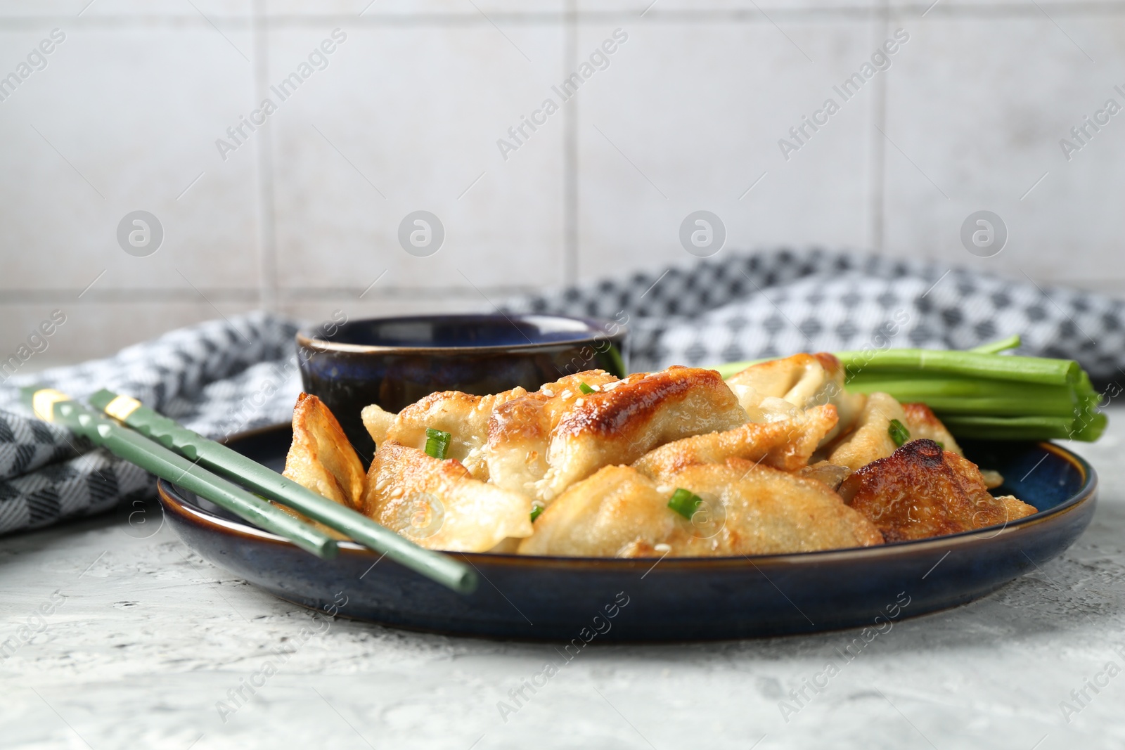 Photo of Tasty fried gyoza (dumplings) and soy sauce on light grey table, closeup