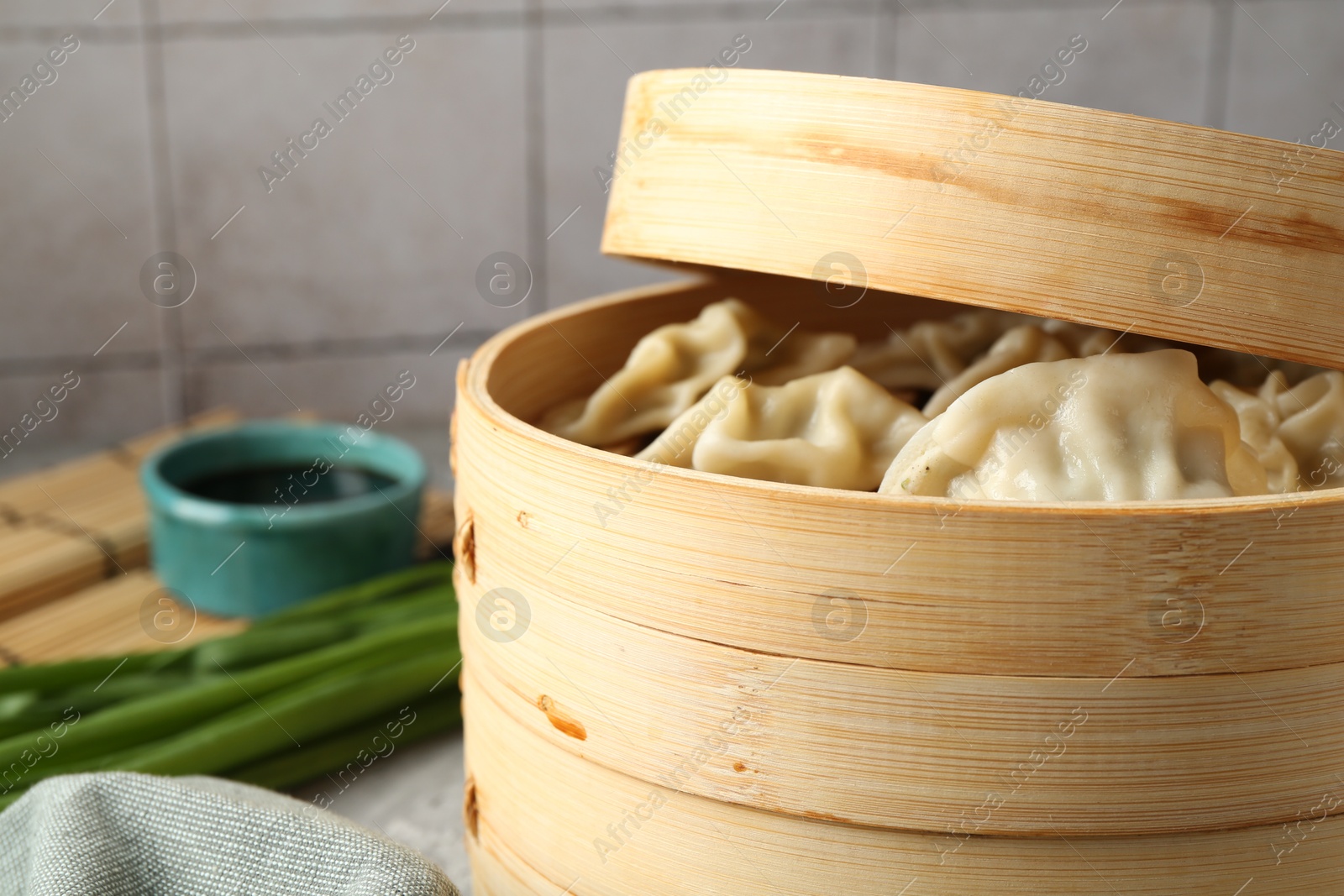 Photo of Tasty boiled gyoza (dumplings) in bamboo steamer on table, closeup