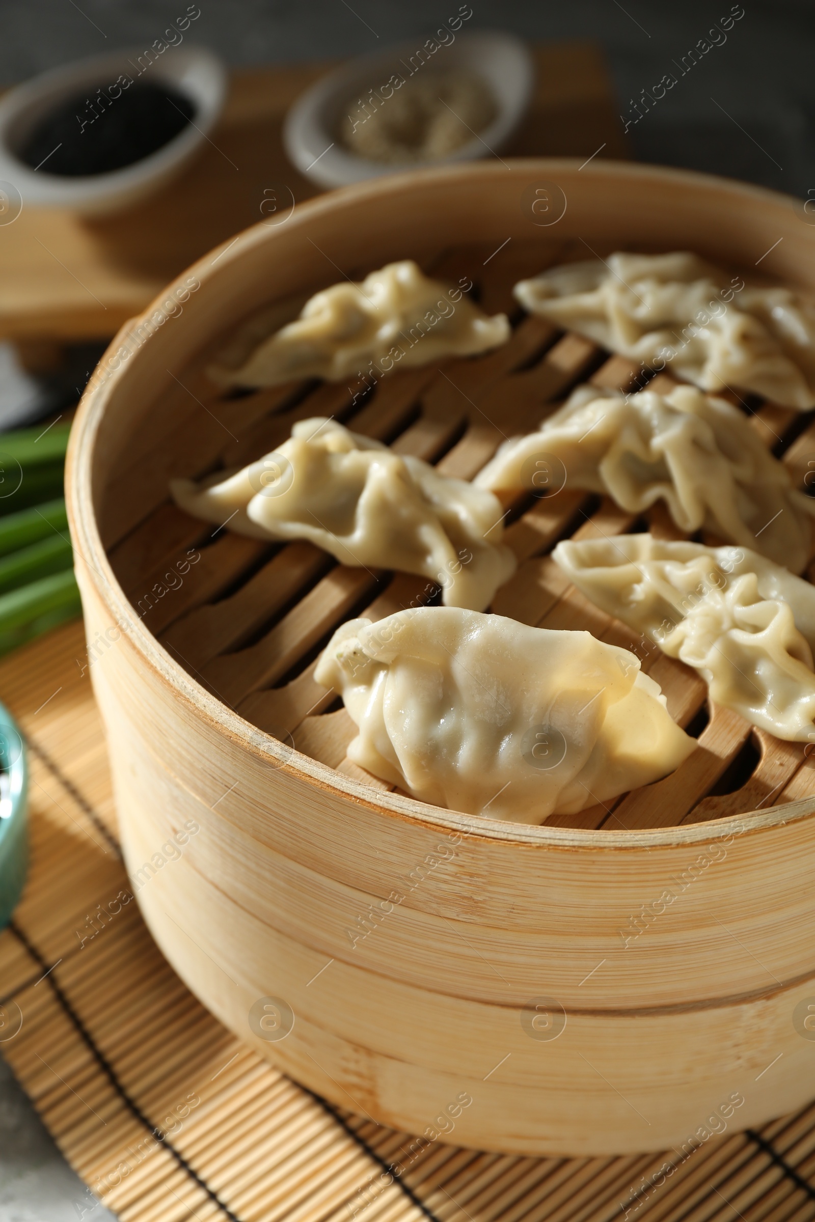 Photo of Tasty boiled gyoza (dumplings) in bamboo steamer on table, closeup