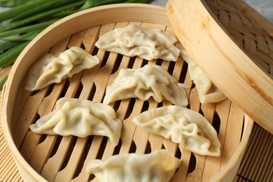 Photo of Tasty boiled gyoza (dumplings) in bamboo steamer on table, closeup