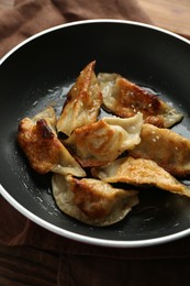 Photo of Tasty fried gyoza (dumplings) on wooden table, closeup