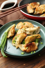 Photo of Tasty fried gyoza (dumplings) on wooden table, closeup