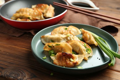 Photo of Tasty fried gyoza (dumplings) on wooden table, closeup