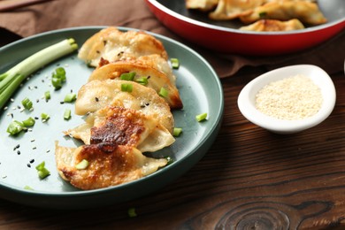 Photo of Tasty fried gyoza (dumplings) on wooden table, closeup