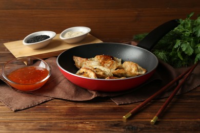 Photo of Tasty fried gyoza (dumplings) and sauce on wooden table, closeup