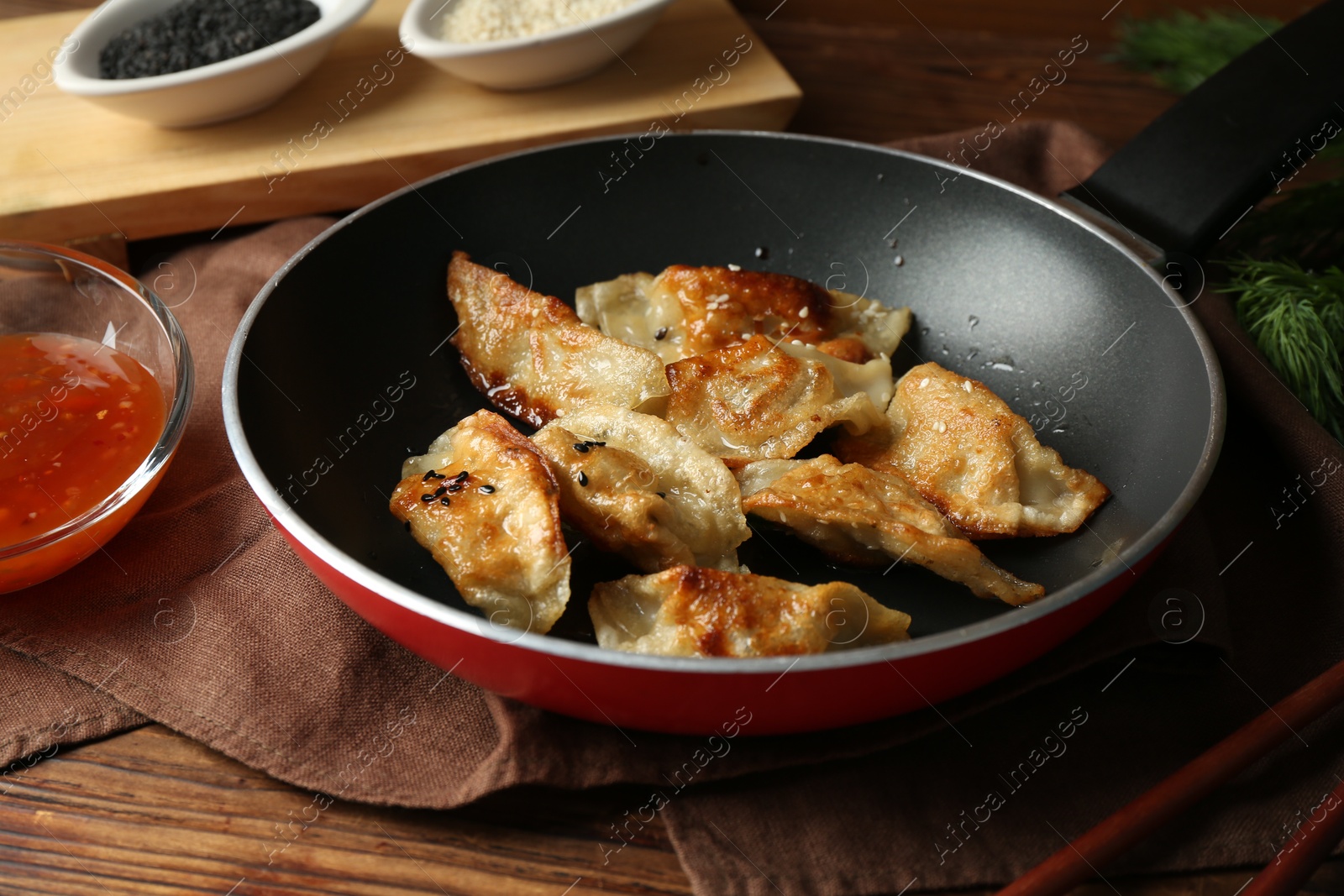 Photo of Tasty fried gyoza (dumplings) and sauce on wooden table, closeup