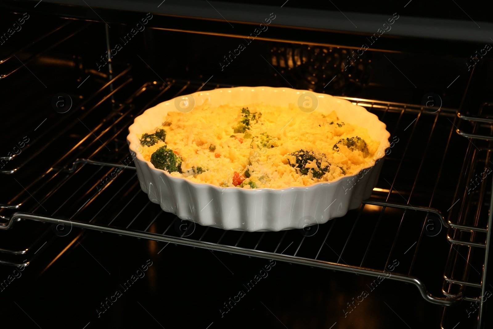 Photo of Baking dish with uncooked vegetable casserole in oven