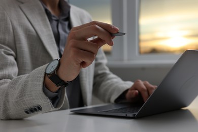 Photo of Electronic signature. Man with stylus and laptop at white table indoors, closeup