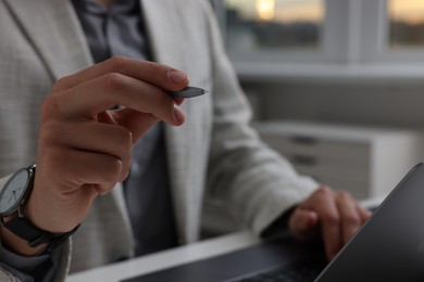 Photo of Electronic signature. Man with stylus and laptop at table indoors, closeup