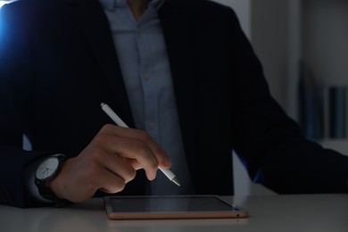 Photo of Electronic signature. Man with stylus and tablet at table indoors, closeup