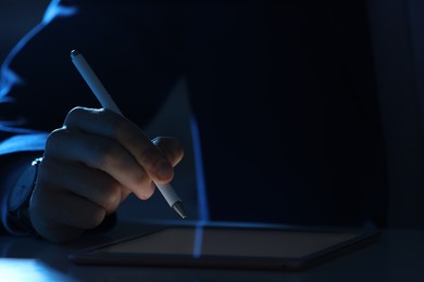 Photo of Electronic signature. Man with stylus and tablet at table in dark office, closeup