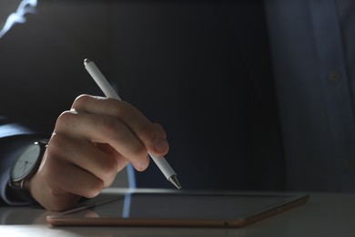 Photo of Electronic signature. Man with stylus and tablet at table indoors, closeup