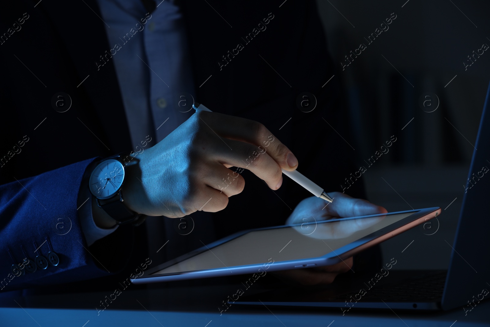 Photo of Electronic signature. Man with stylus, tablet and laptop at table in dark office, closeup