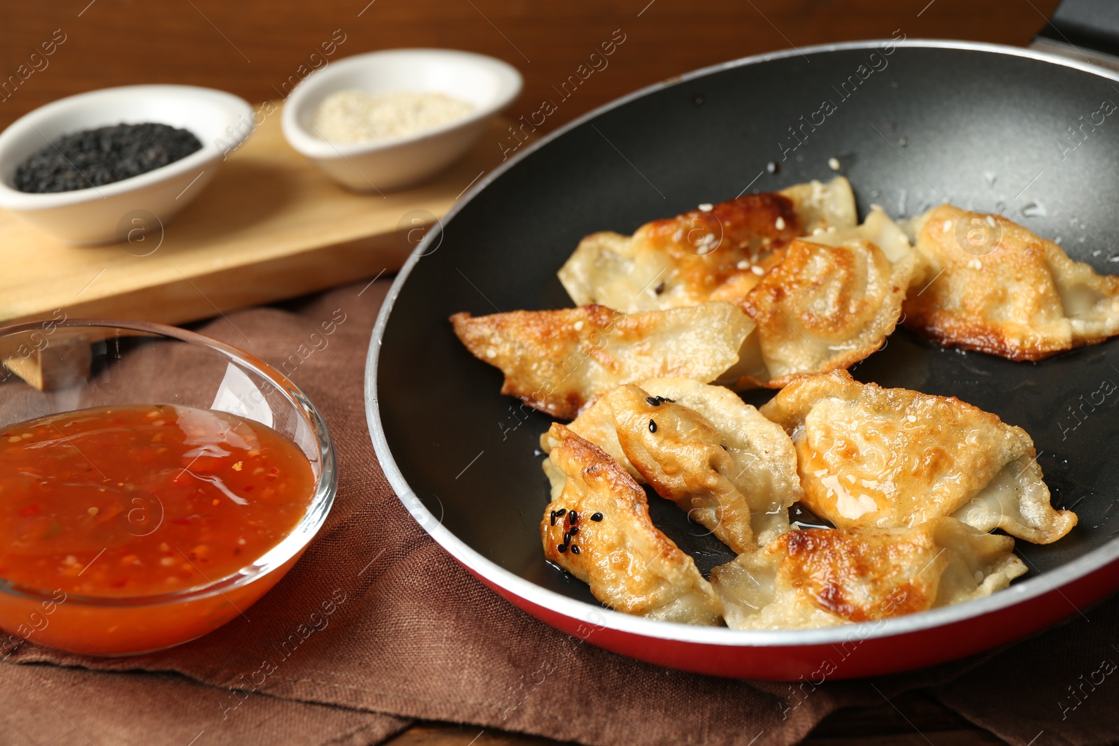 Photo of Tasty fried gyoza (dumplings) and sauce on wooden table, closeup