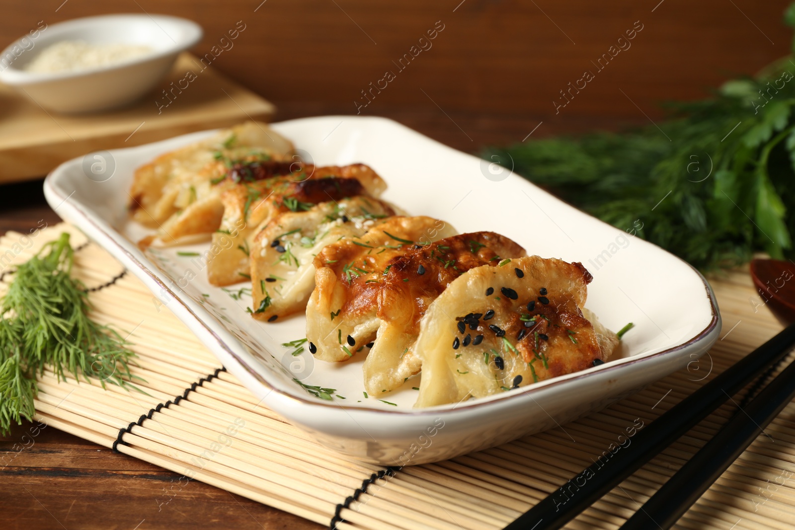 Photo of Tasty fried gyoza (dumplings) and chopsticks on wooden table, closeup