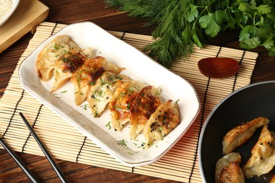 Photo of Tasty fried gyoza (dumplings) and chopsticks on wooden table