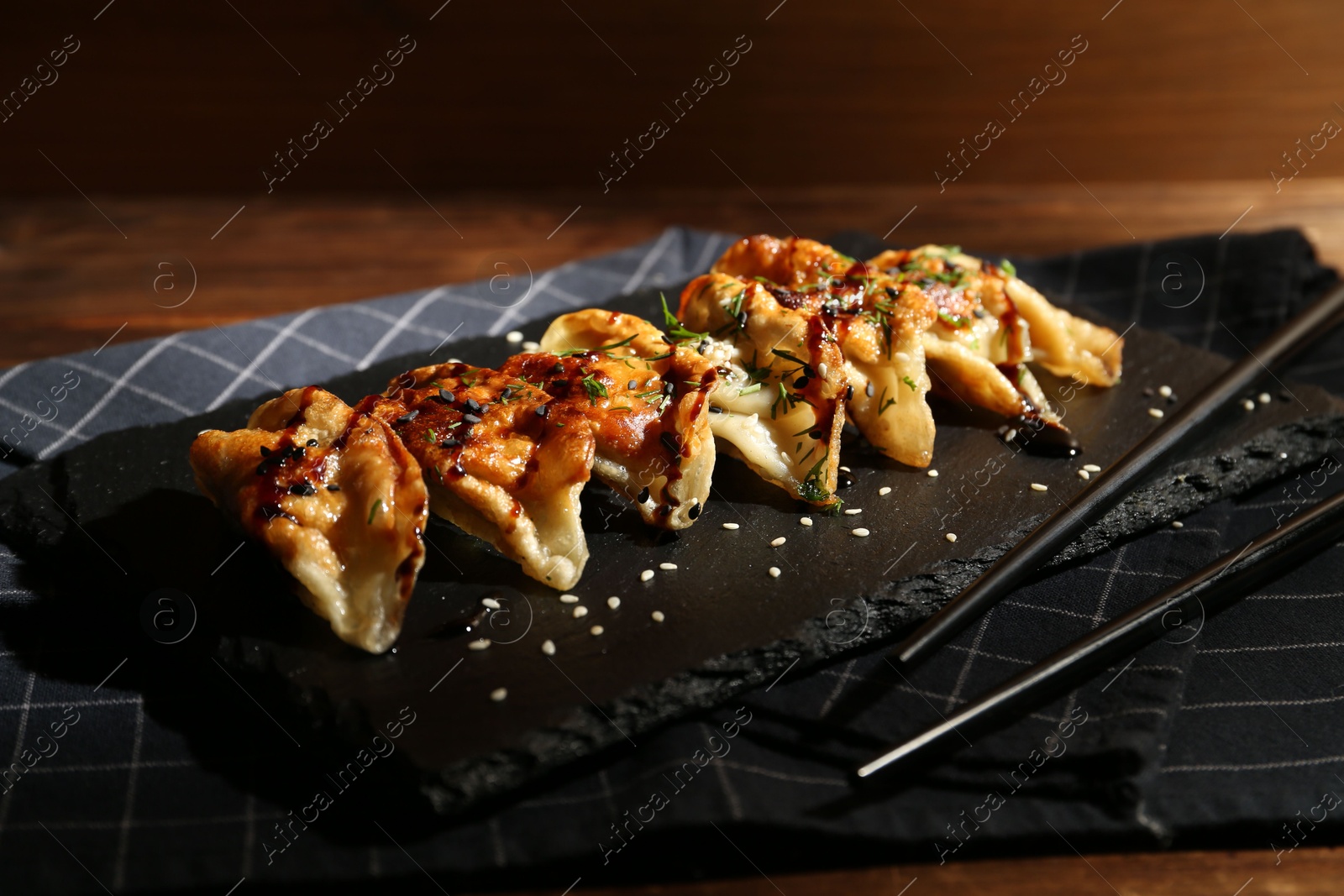 Photo of Tasty fried gyoza (dumplings) and chopsticks on wooden table, closeup