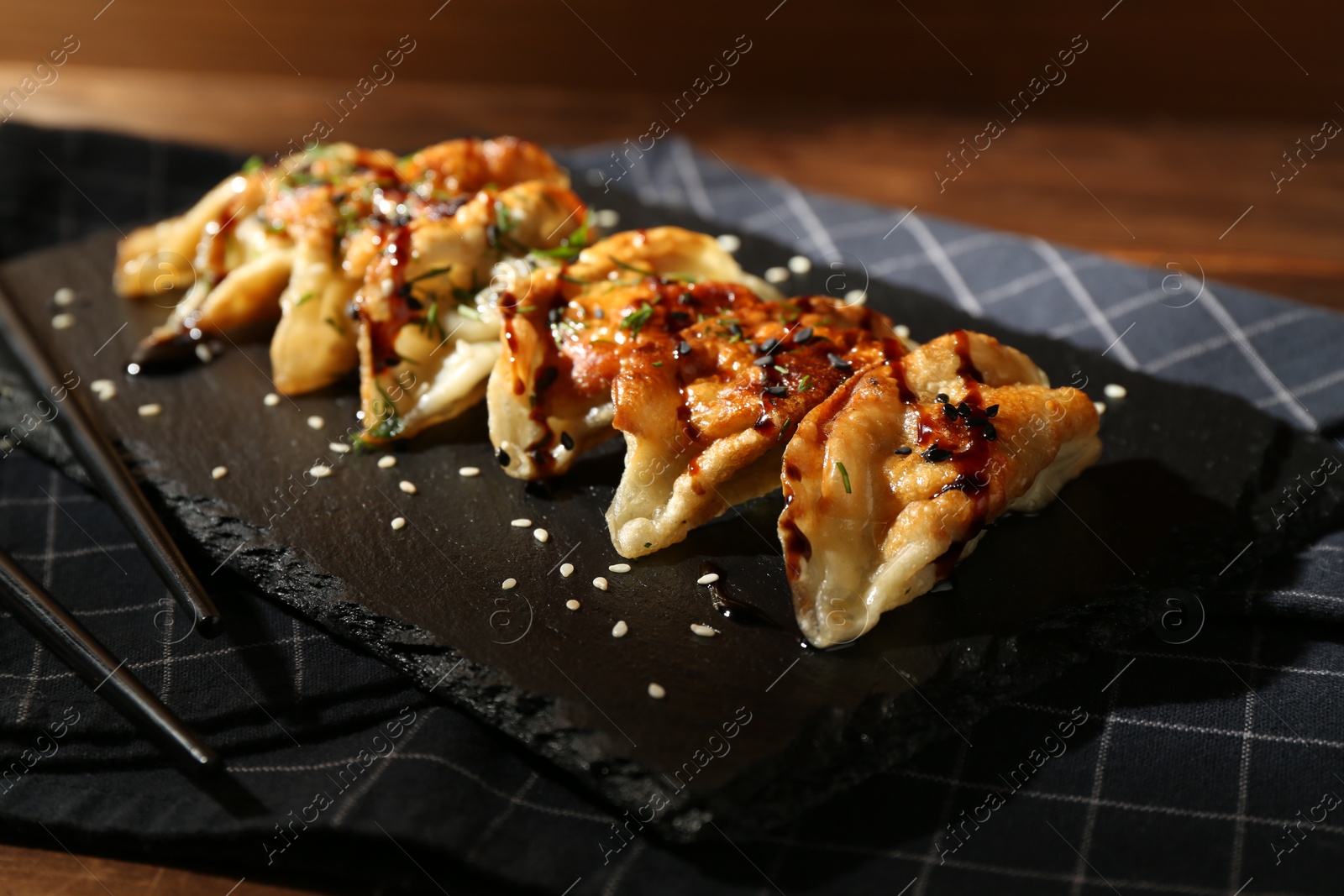 Photo of Tasty fried gyoza (dumplings) and chopsticks on wooden table, closeup