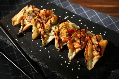 Photo of Tasty fried gyoza (dumplings) and chopsticks on table, closeup