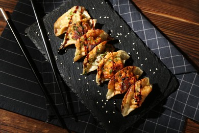 Photo of Tasty fried gyoza (dumplings) and chopsticks on wooden table, top view