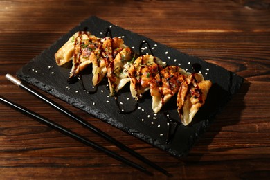 Photo of Tasty fried gyoza (dumplings) and chopsticks on wooden table