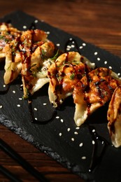 Photo of Tasty fried gyoza (dumplings) and chopsticks on wooden table, closeup