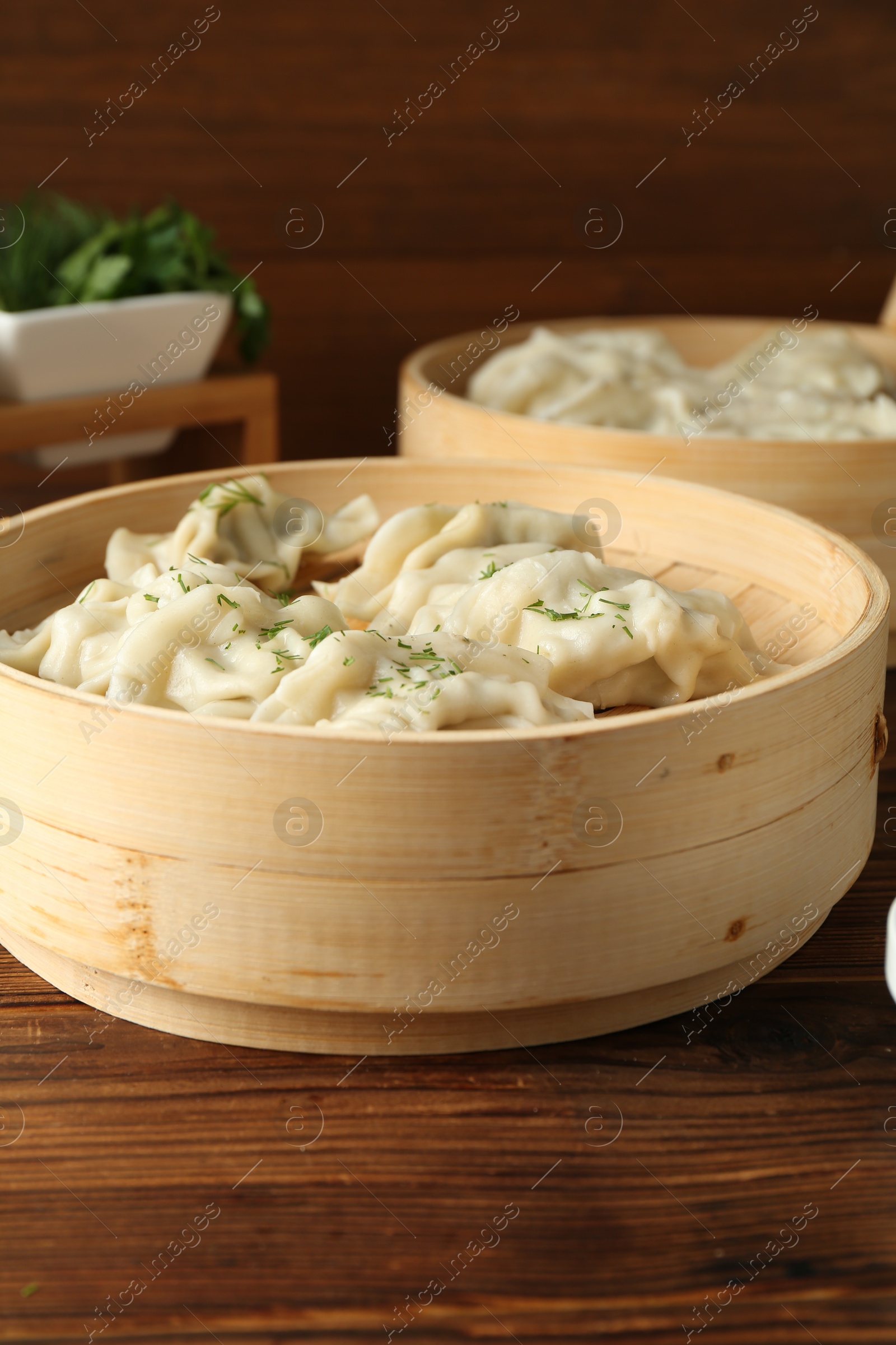 Photo of Tasty boiled gyoza (dumplings) in bamboo steamers on wooden table, closeup