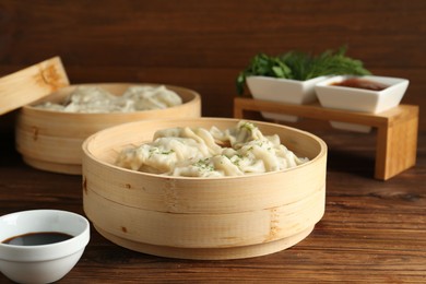 Photo of Tasty boiled gyoza (dumplings) in bamboo steamers on wooden table, closeup