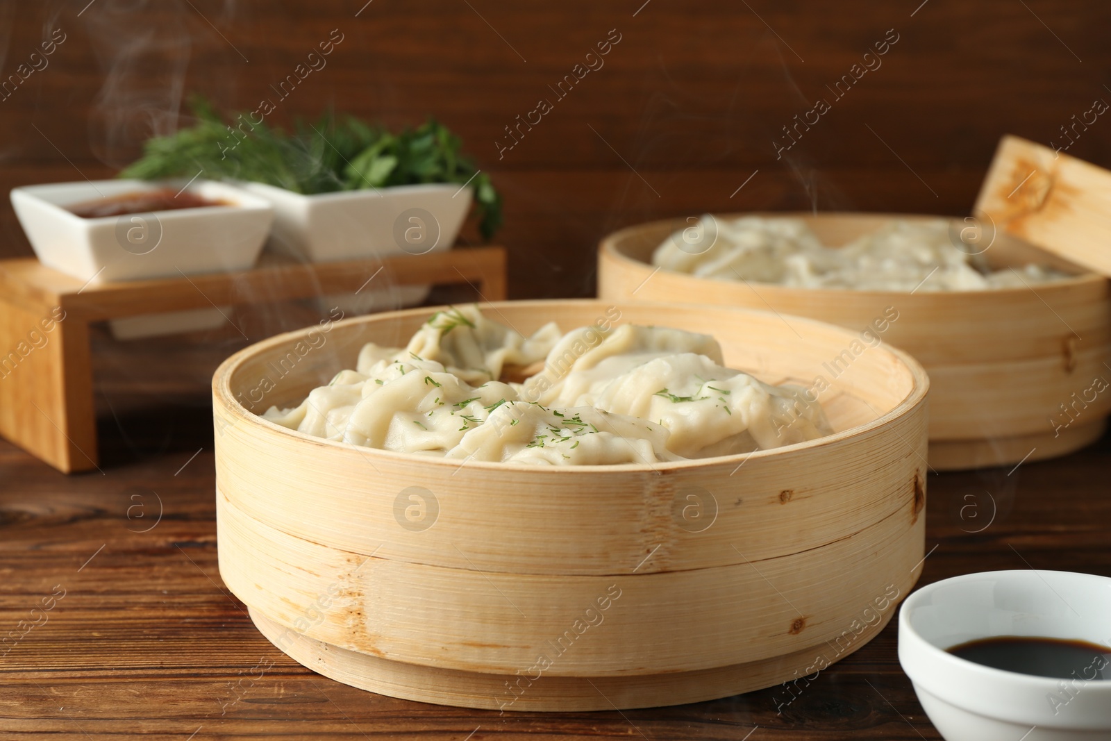 Photo of Tasty boiled gyoza (dumplings) in bamboo steamers on wooden table, closeup