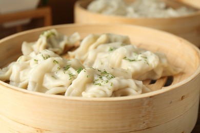 Photo of Tasty boiled gyoza (dumplings) in bamboo steamers on table, closeup