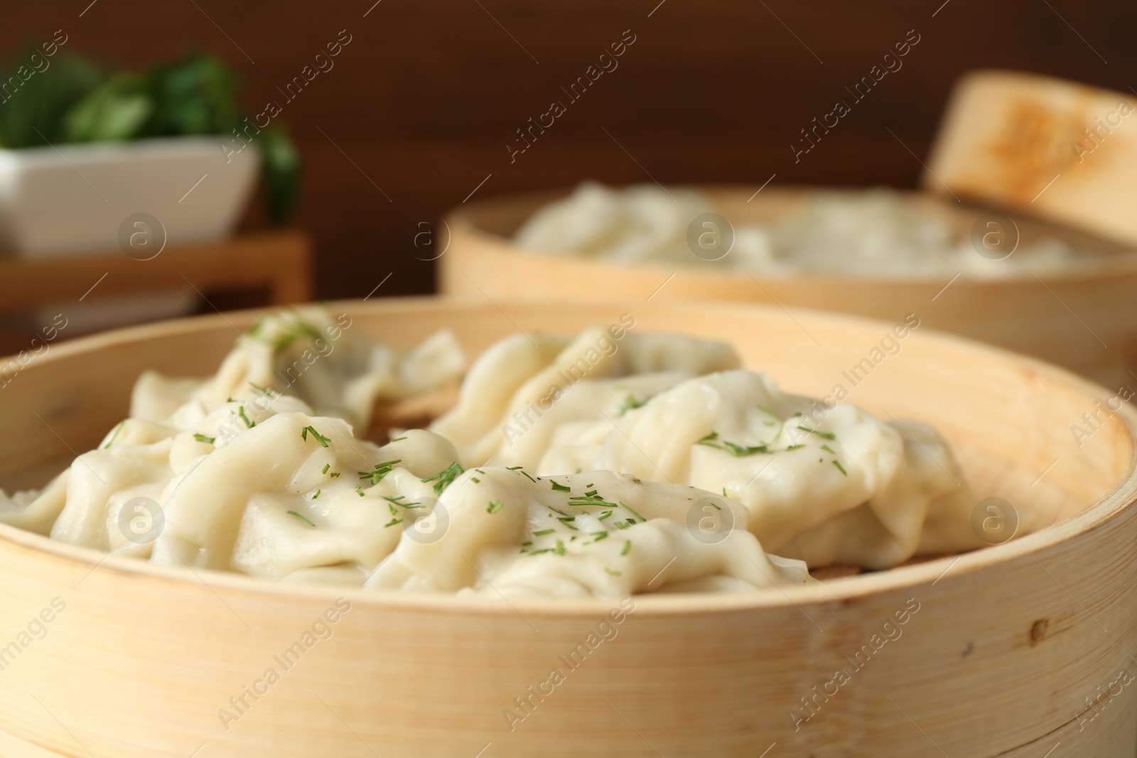 Photo of Tasty boiled gyoza (dumplings) in bamboo steamers on table, closeup