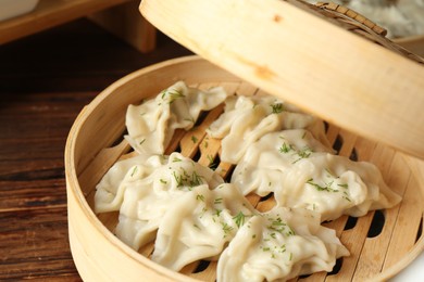 Photo of Tasty boiled gyoza (dumplings) in bamboo steamer on wooden table, closeup