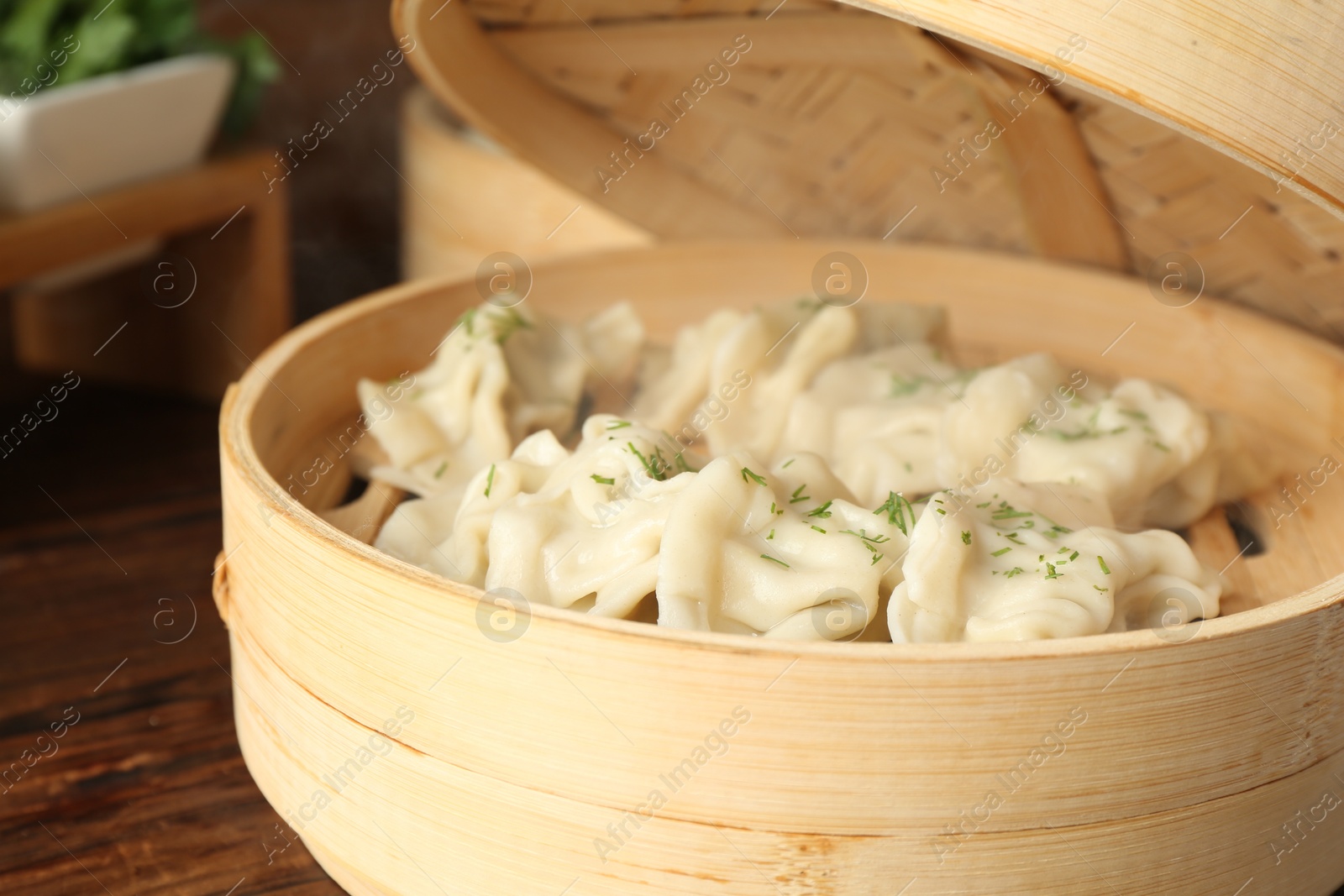 Photo of Tasty boiled gyoza (dumplings) in bamboo steamer on wooden table, closeup