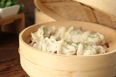 Photo of Tasty boiled gyoza (dumplings) in bamboo steamer on wooden table, closeup