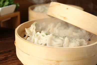 Photo of Tasty boiled gyoza (dumplings) in bamboo steamers on wooden table, closeup