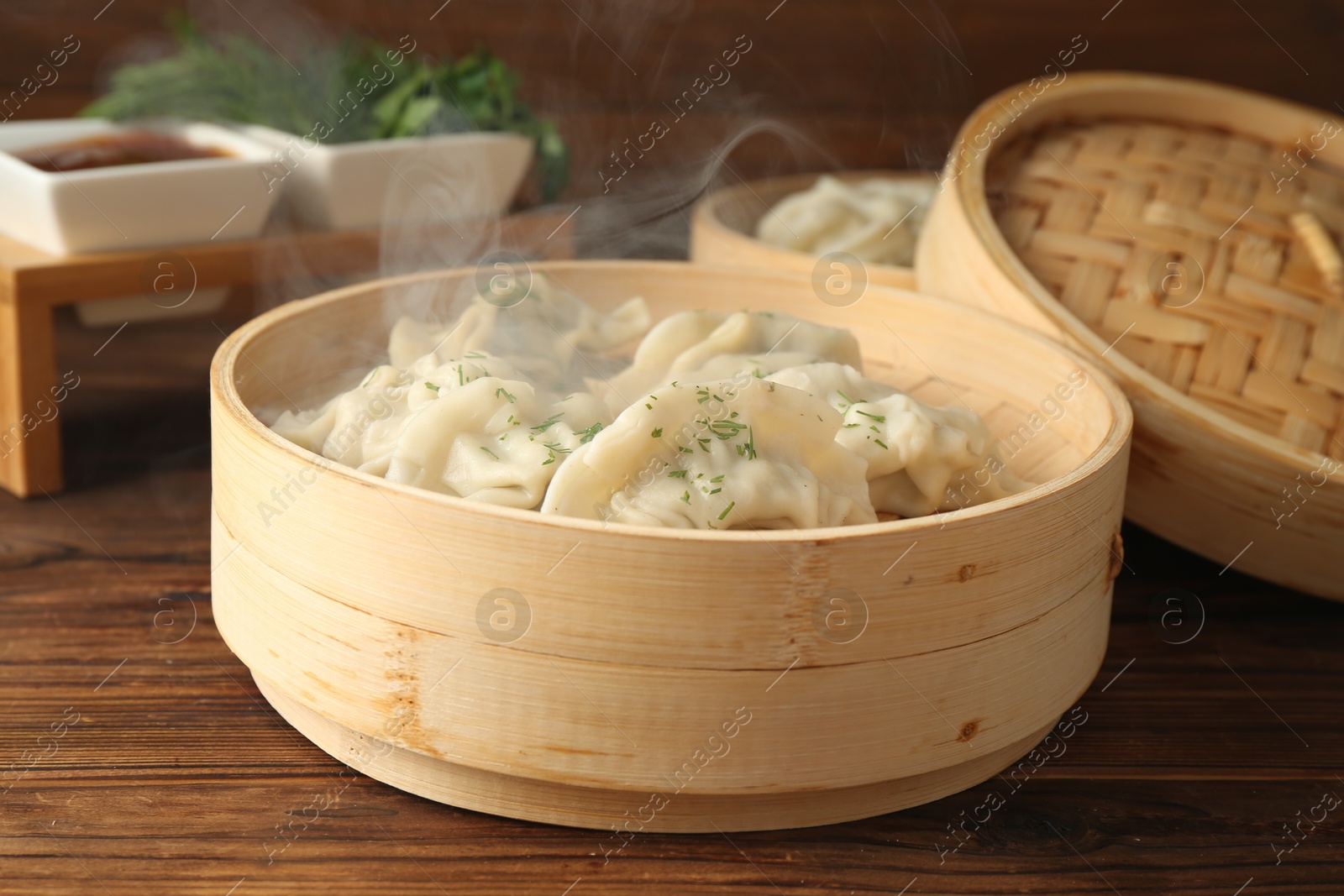 Photo of Tasty boiled gyoza (dumplings) in bamboo steamers on wooden table, closeup