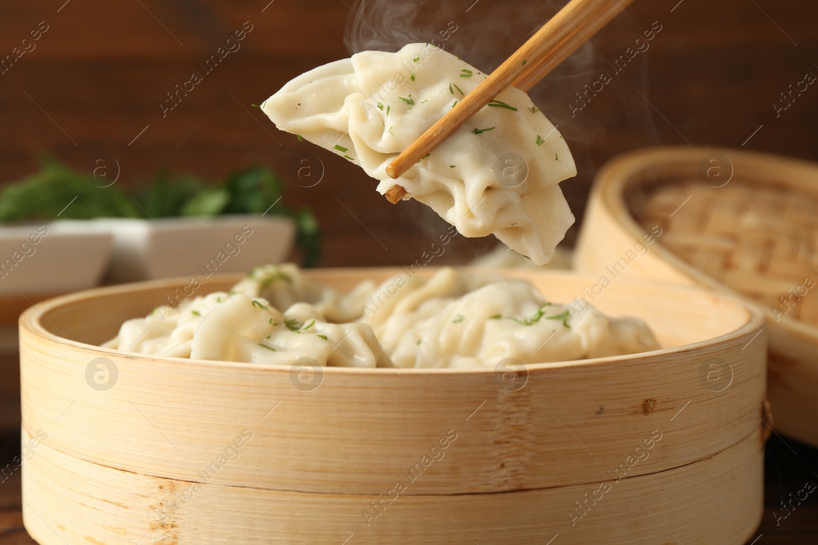 Photo of Taking tasty boiled gyoza (dumpling) with chopsticks on table, closeup