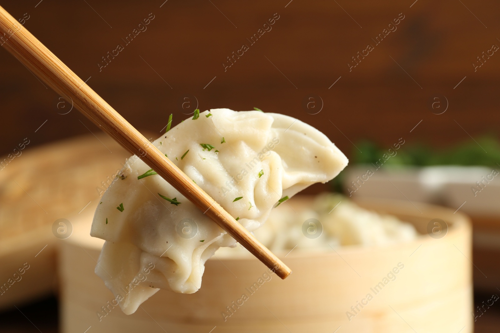 Photo of Taking tasty boiled gyoza (dumpling) with chopsticks on table, closeup