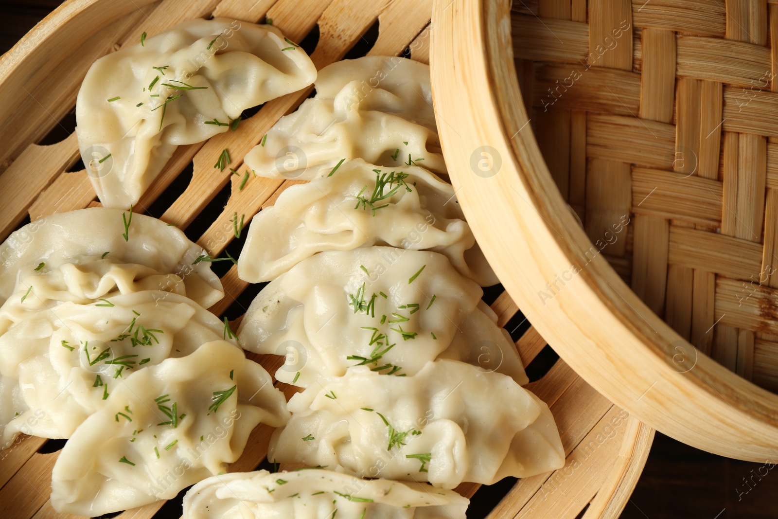 Photo of Tasty boiled gyoza (dumplings) in bamboo steamer on wooden table, top view