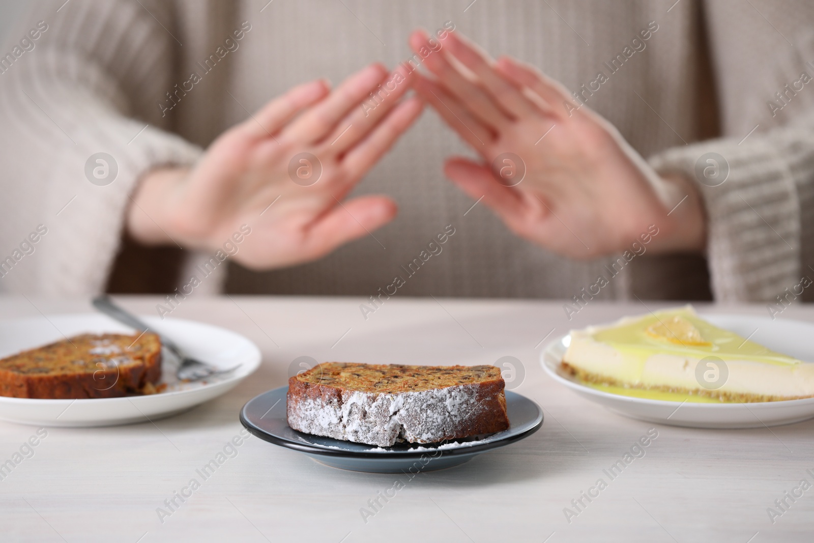 Photo of Woman refusing to eat products at table indoors, selective focus. Food allergy concept