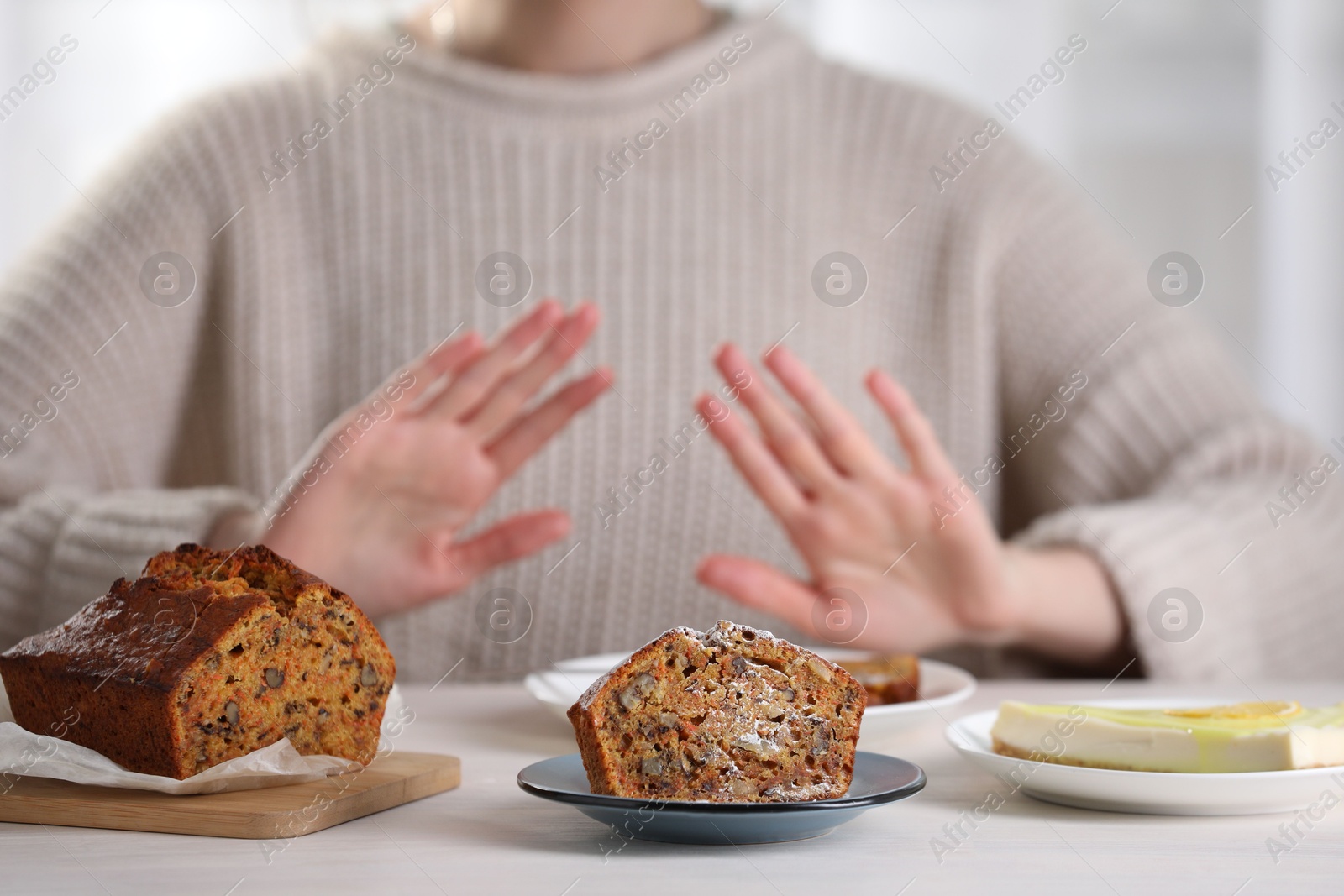 Photo of Woman refusing to eat products at table indoors, selective focus. Food allergy concept