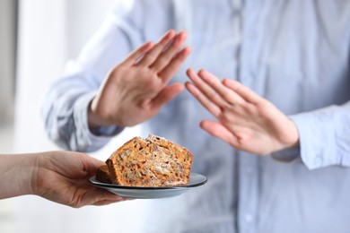 Photo of Woman refusing carrot cake indoors, selective focus. Food allergy concept