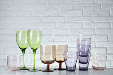 Photo of Many different glasses on white marble table against brick wall. Space for text